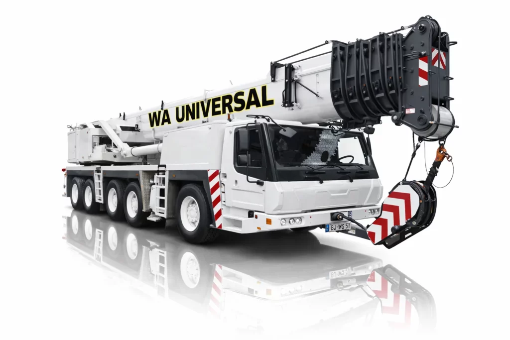 A large white mobile crane with "WA UNIVERSAL" written on its extended boom, featuring multiple wheels, red and white safety stripes, and a heavy-duty hook, reflected on a glossy surface.